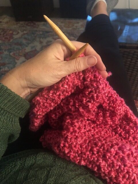 hand holding knitting needle and yarn