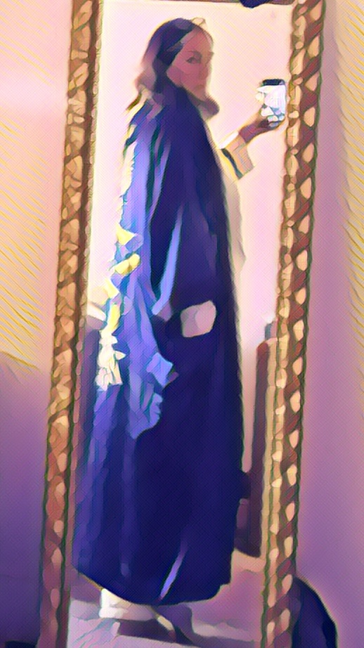 Woman in robe standing back-to in a mirror